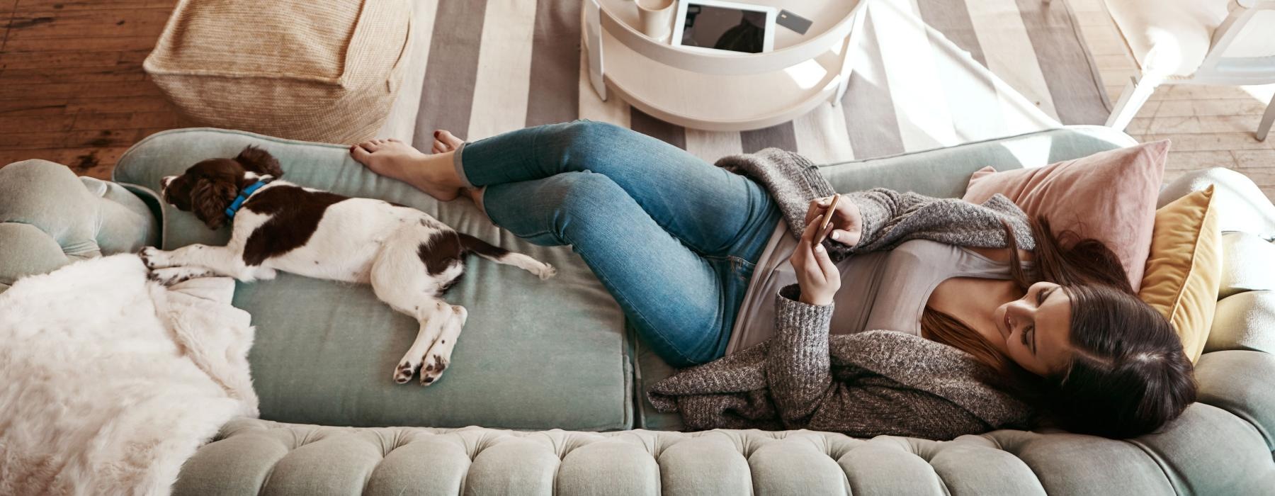 a person lying on a couch with a dog